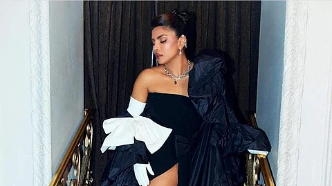 Priyanka Chopra Jonas wore a Valentino black cady strapless dress with black bow detail and leather gloves along with a black faille cape with a white bow.