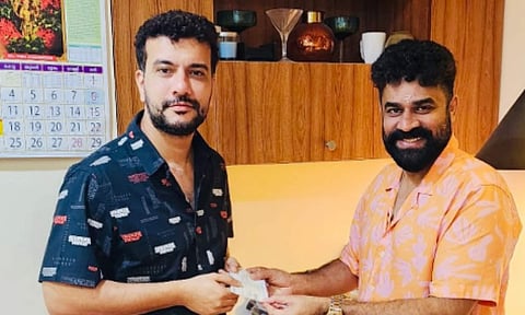 The photo features Vijay Babu handing over an advance cheque to Ramesh Pisharody